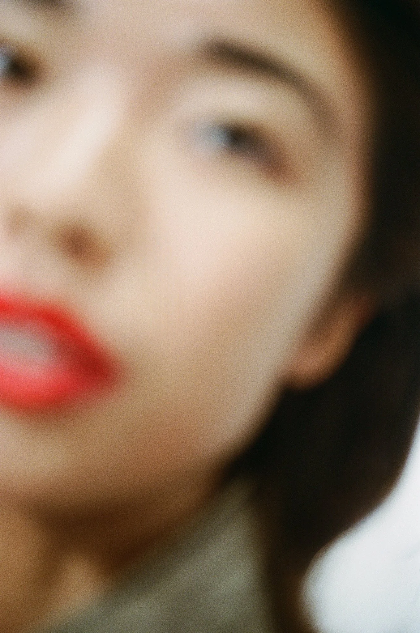 Close-up of a person's face, showing part of the eye, cheek, and lipstick, with blurred surroundings.