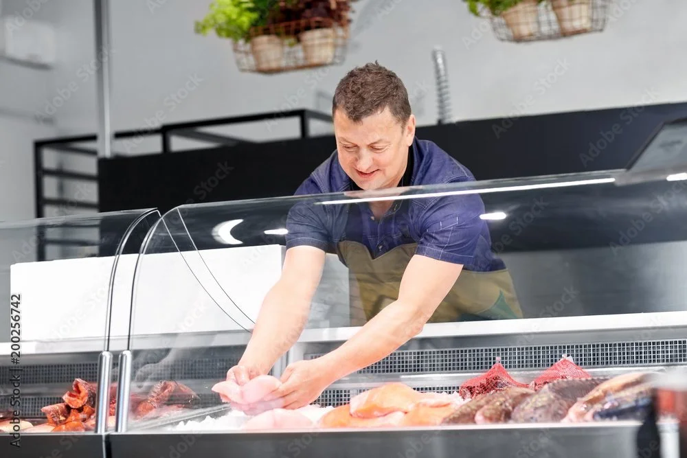 L&B Butcher stands up and out of the display case and we transition the whole salmon into a generous sized salmon fillet on a cedar plank with lemons. (Match action Bolt camera move following the whole salmon to the cedar plank salmon)