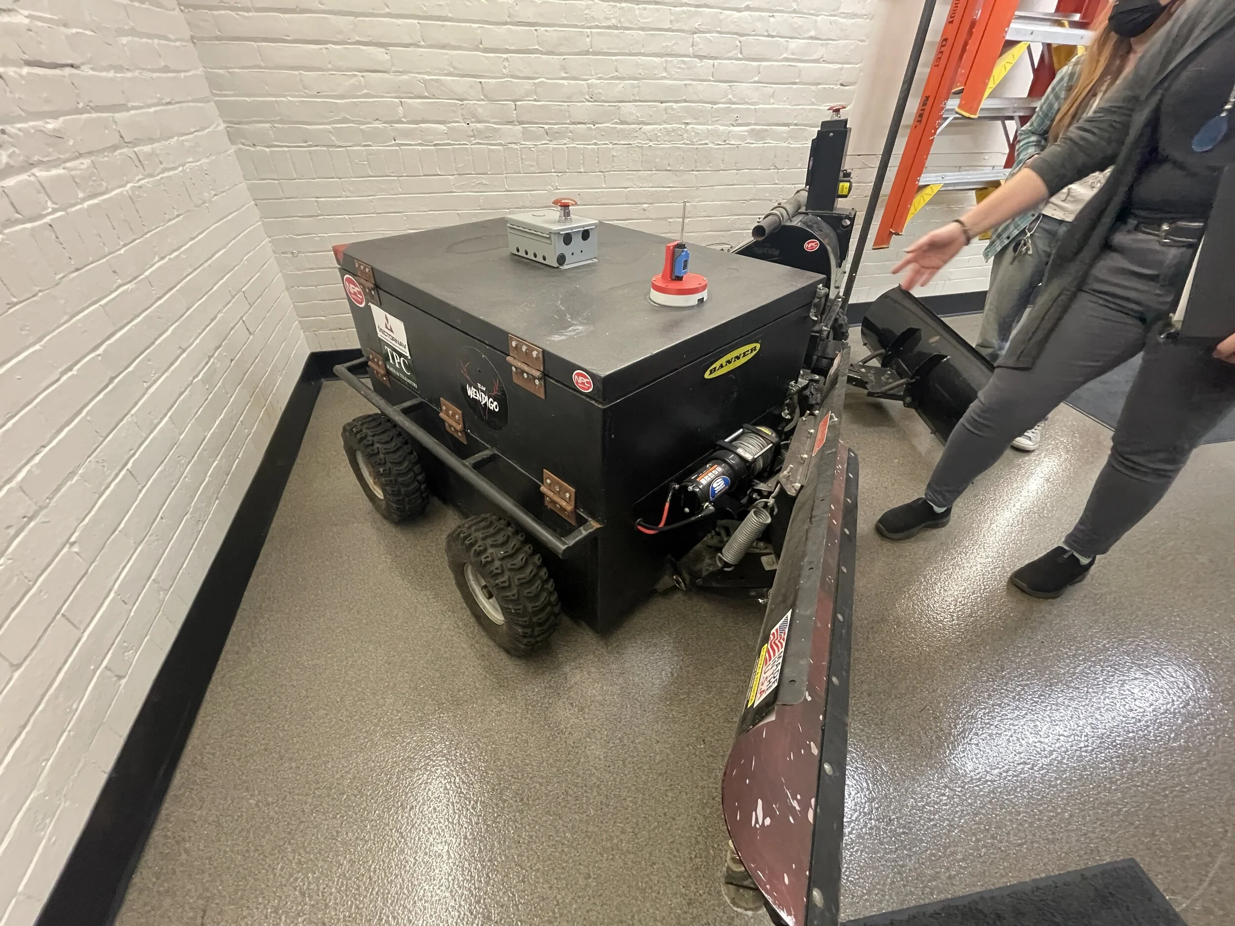 A008 - Low tracking shot left to right of 
ACTION: Autonomous Snowplow moving across the parking lot or inside a garage