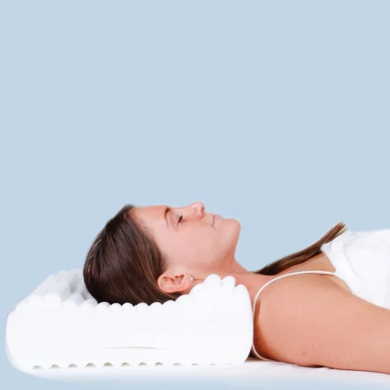 A female in bed on her back with her neck held in correct alignment by her supportive pillow
