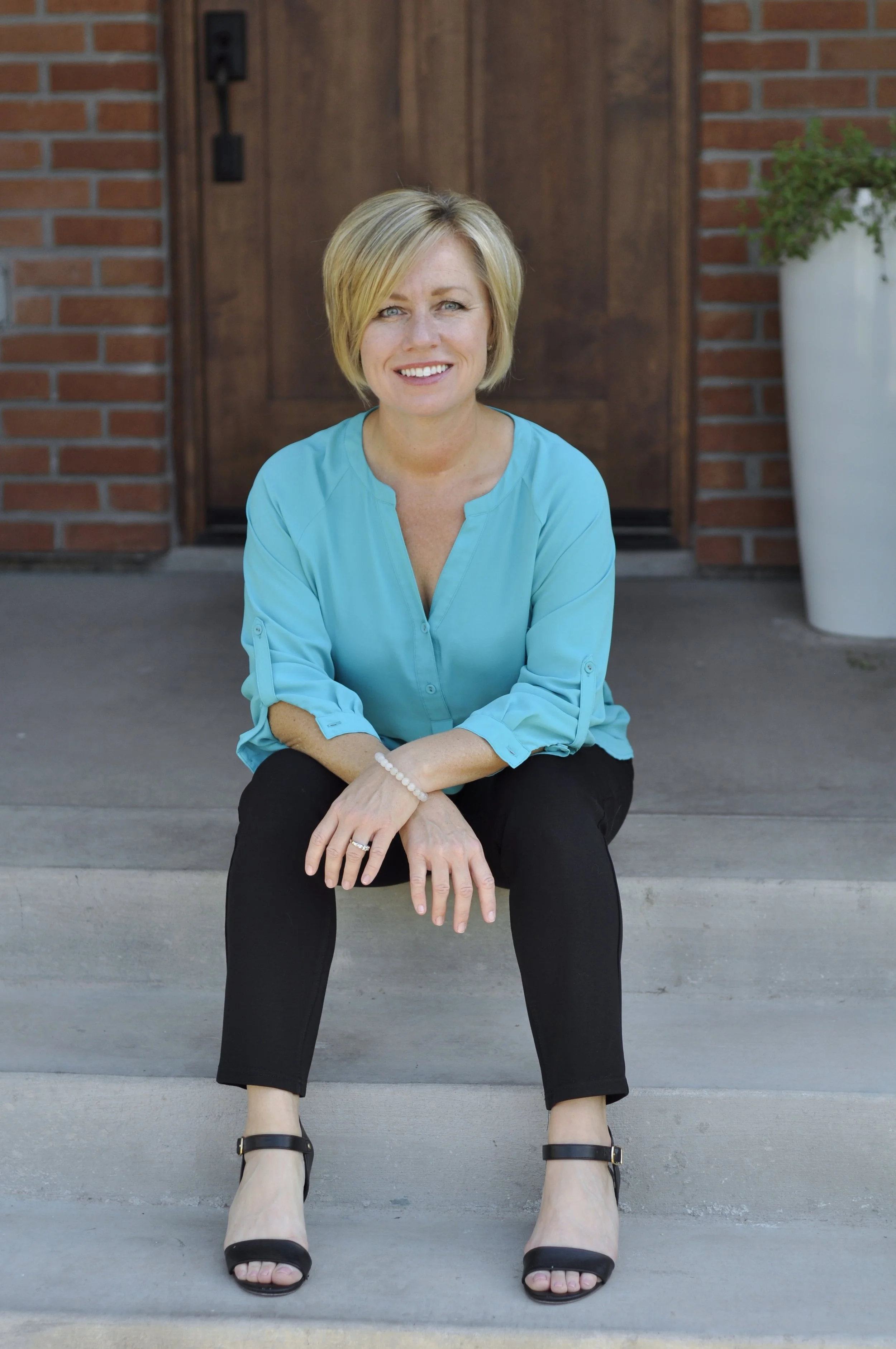 Christy McClendon seated on the steps of a brick building