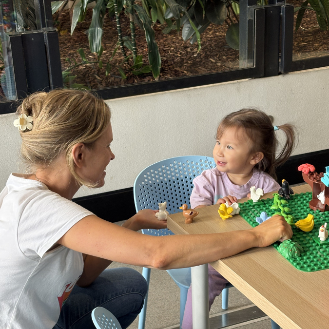 Woman and child smiling at each other while playing with Duplo