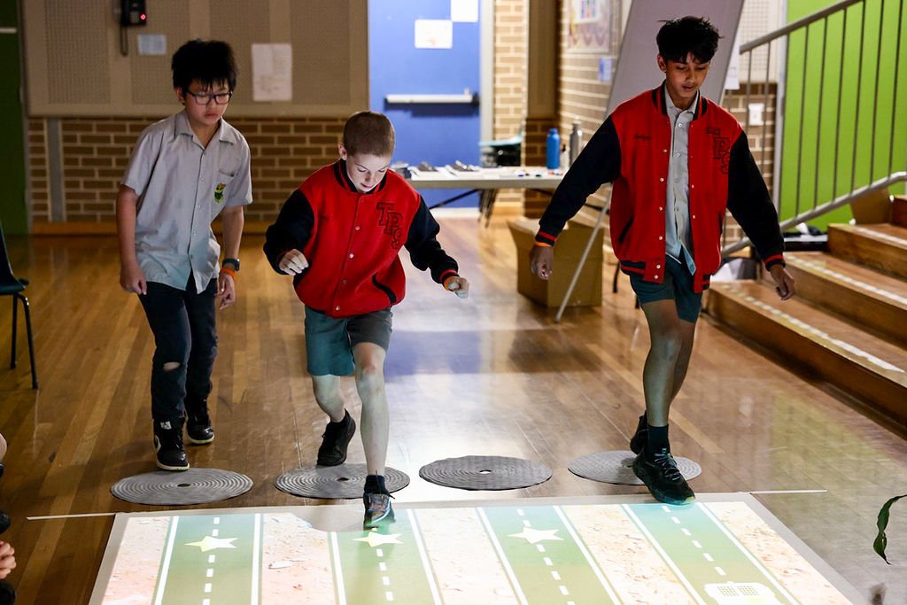three students engaging with an interactive projection