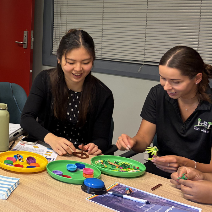 Two women smiling as they play with Lego