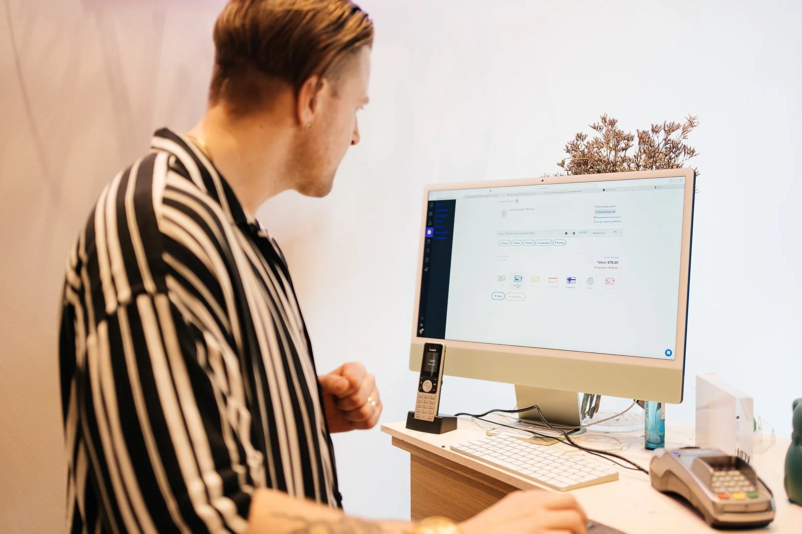 A salon employee looks at the Optios point-of-sale system on the screen at the counter.