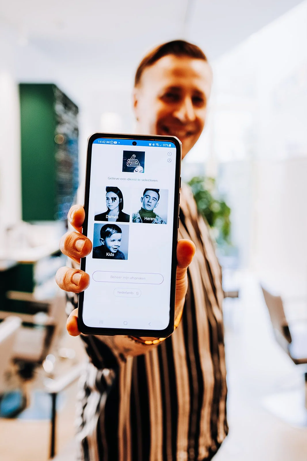 Frau hält Smartphone mit App zur Buchung von Dienstleistungen, mit Fotooptionen für Frauen, Männer und Kinder.
