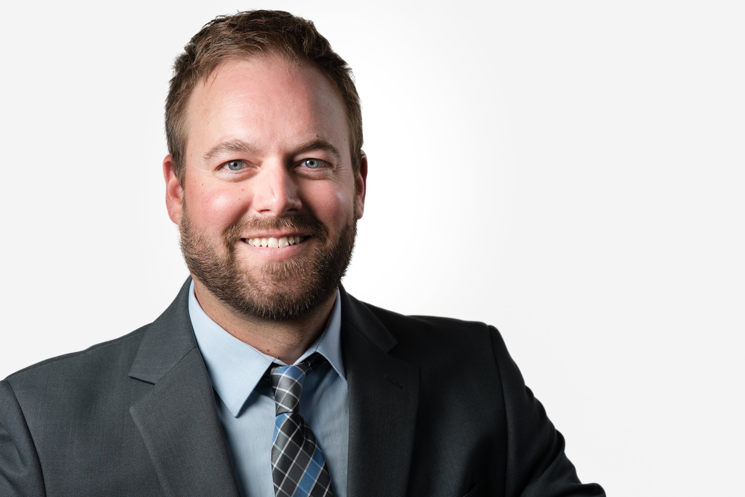 Smiling man in a suit and tie on a white background.