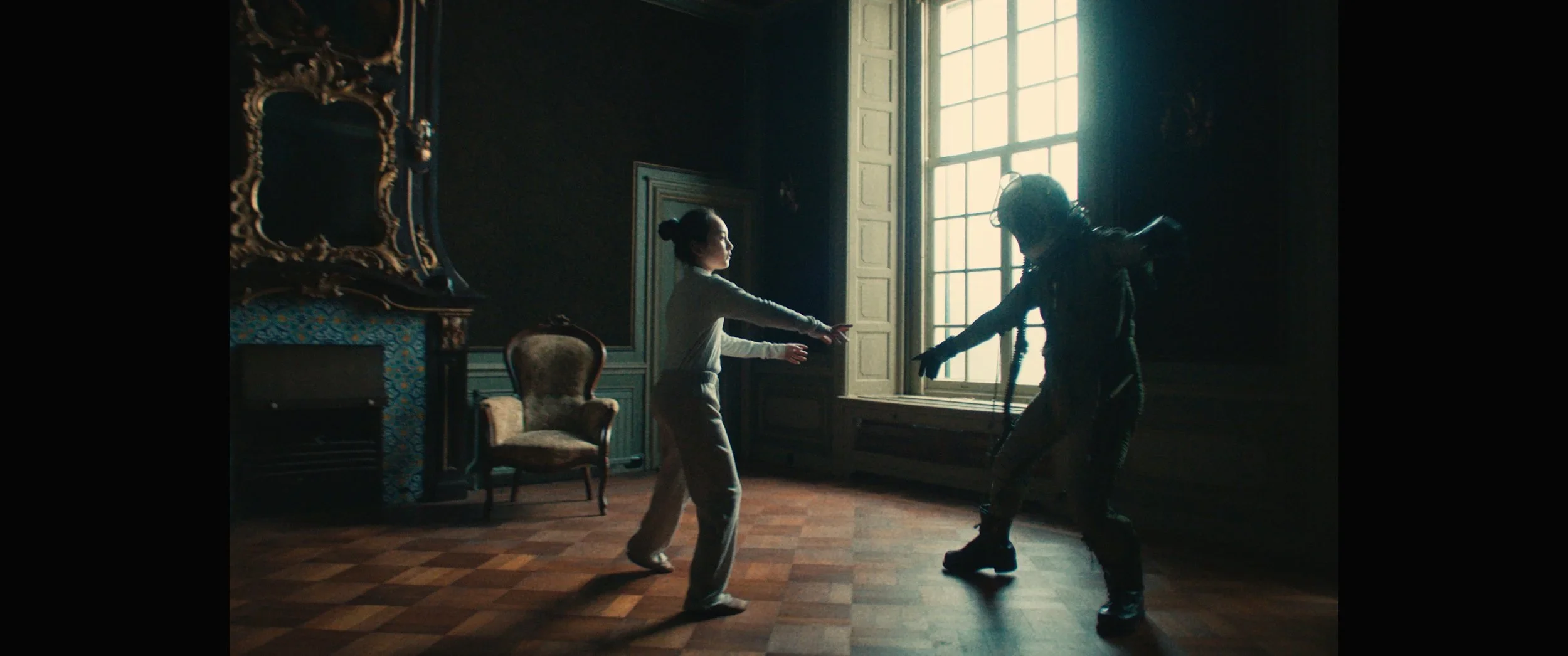 Twee vrouwen dansen in een donkere, klassieke kamer met grote ramen en houten vloer.