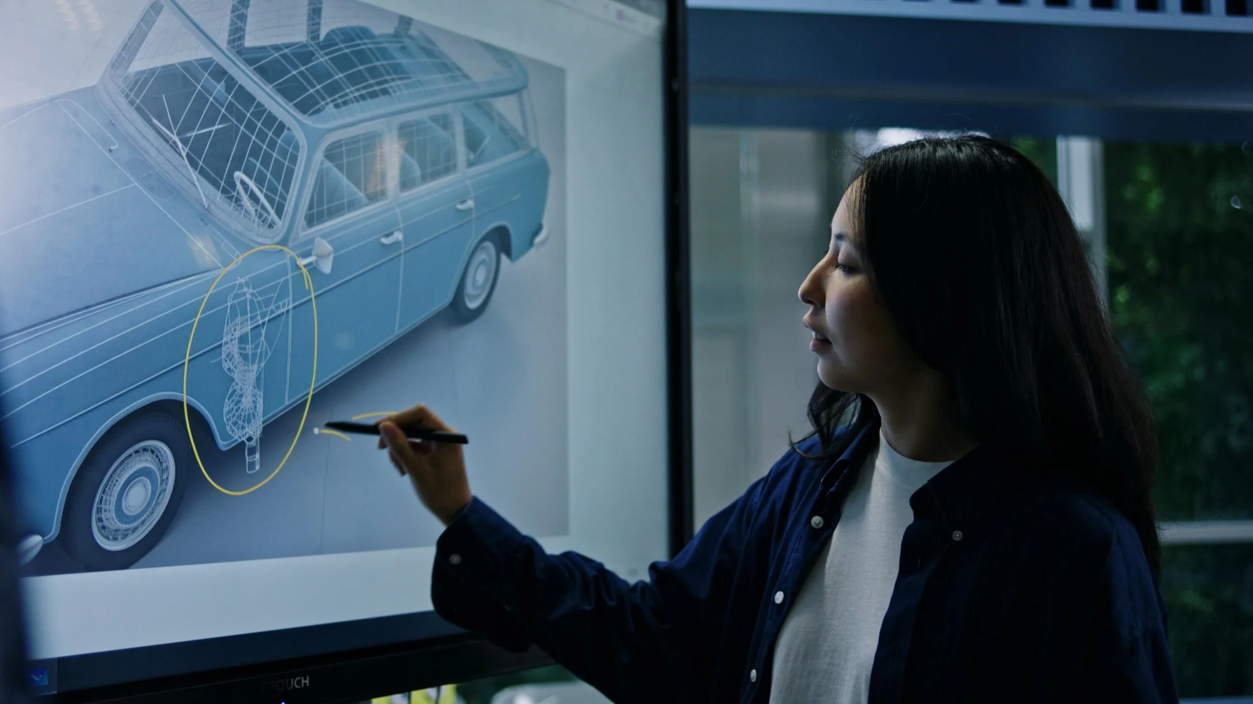 Vrouw tekent een technische tekening van een auto op een digitaal scherm.