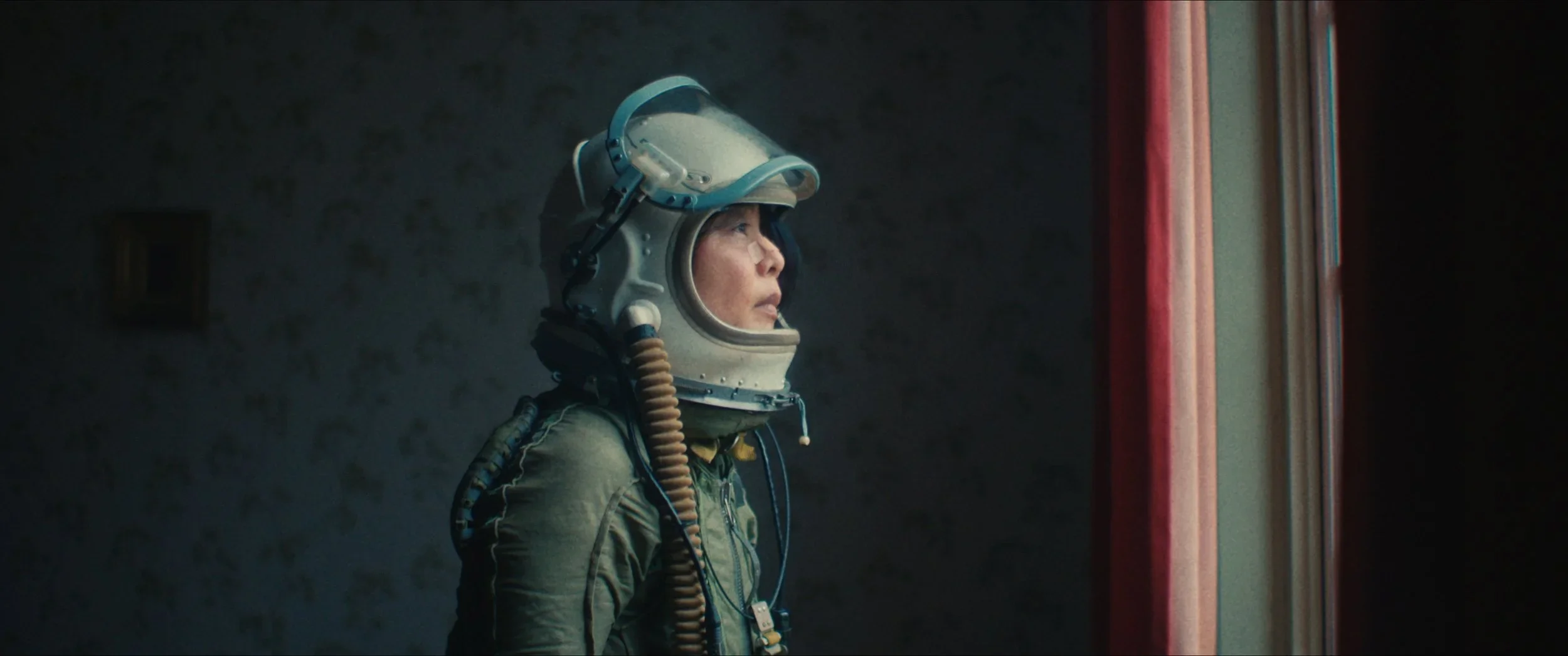 Vrouw in een astronautenruimtepak kijkt uit een raam.