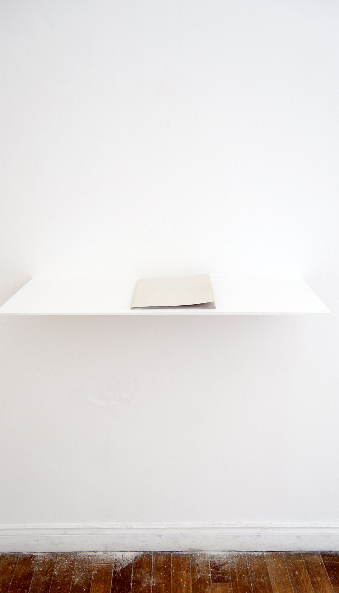 Exhibition view of Limites, artist book by Judith Roux. Digital printing on tracing paper. Displayed on a white shelf set on the wall.