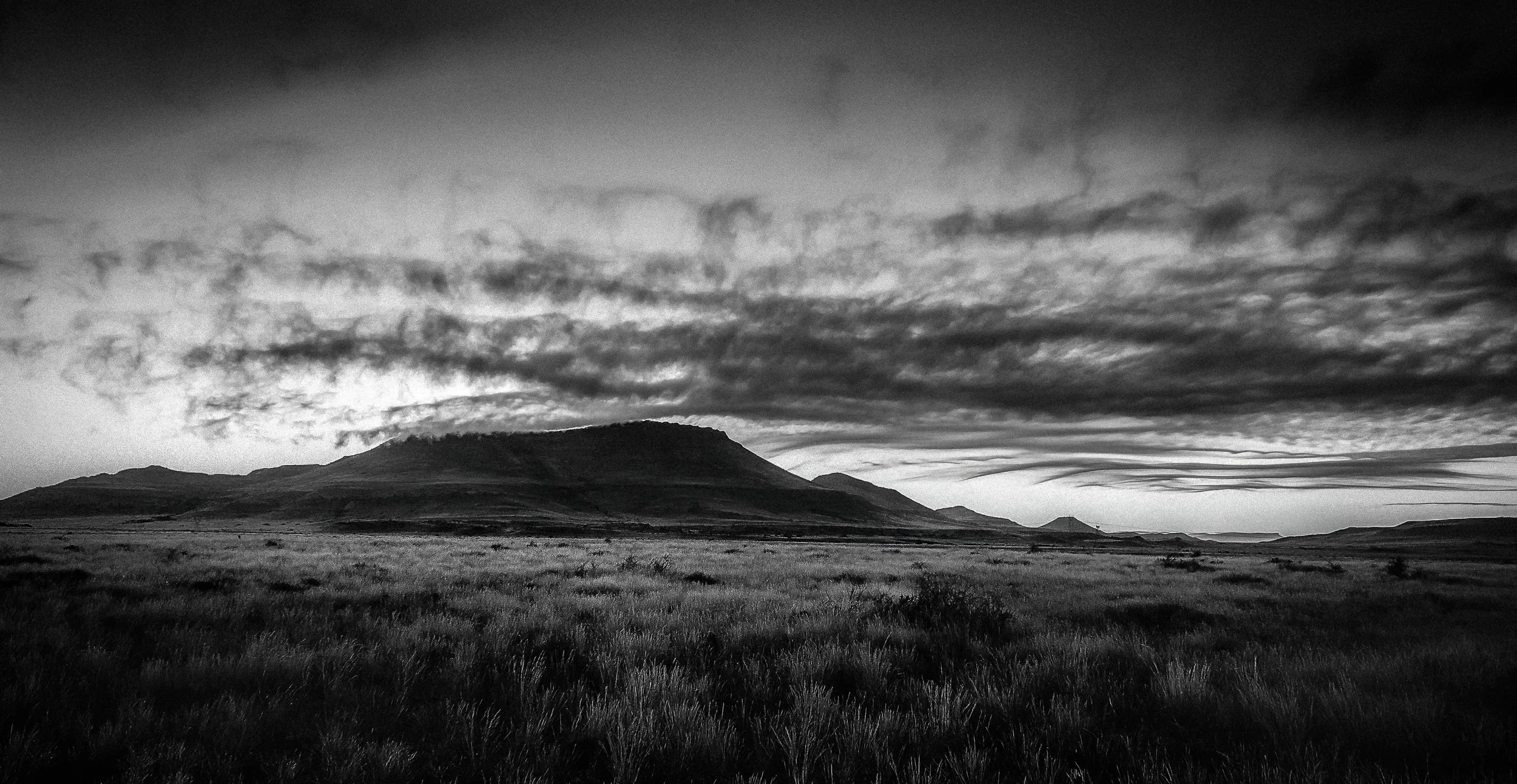 Black and white landscape photograph of a mountain under layered clouds, taken in 2011