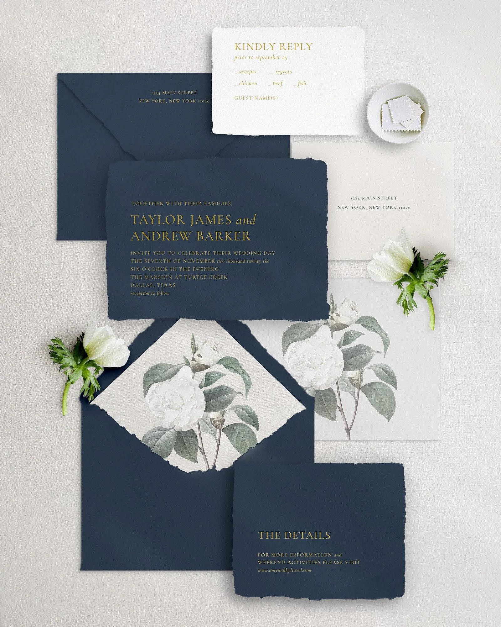 Elegant wedding invitation suite with navy and white paper, featuring floral accents, RSVP card, and envelopes.