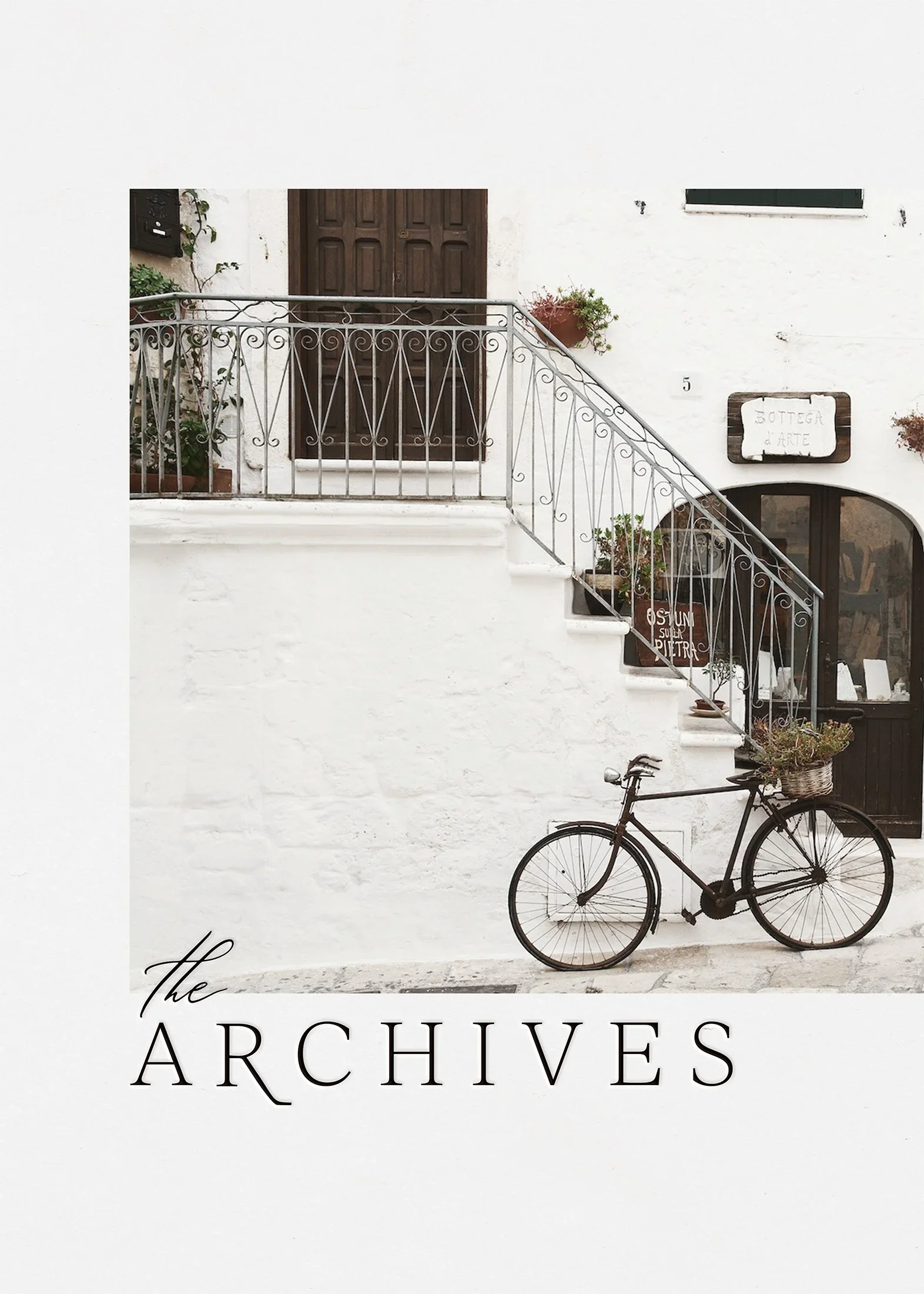 A photo of a white building with a staircase, a bicycle parked against the wall, and the words 'The Archives' at the bottom.