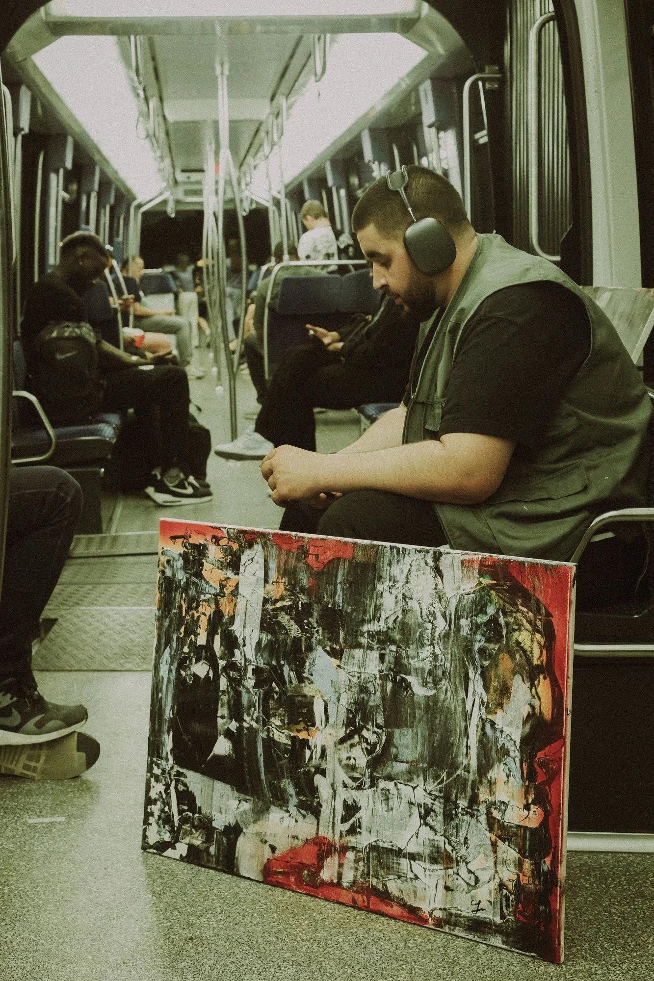 GUNFLAMM dans les transports publics, une toile posée à ses côtés.