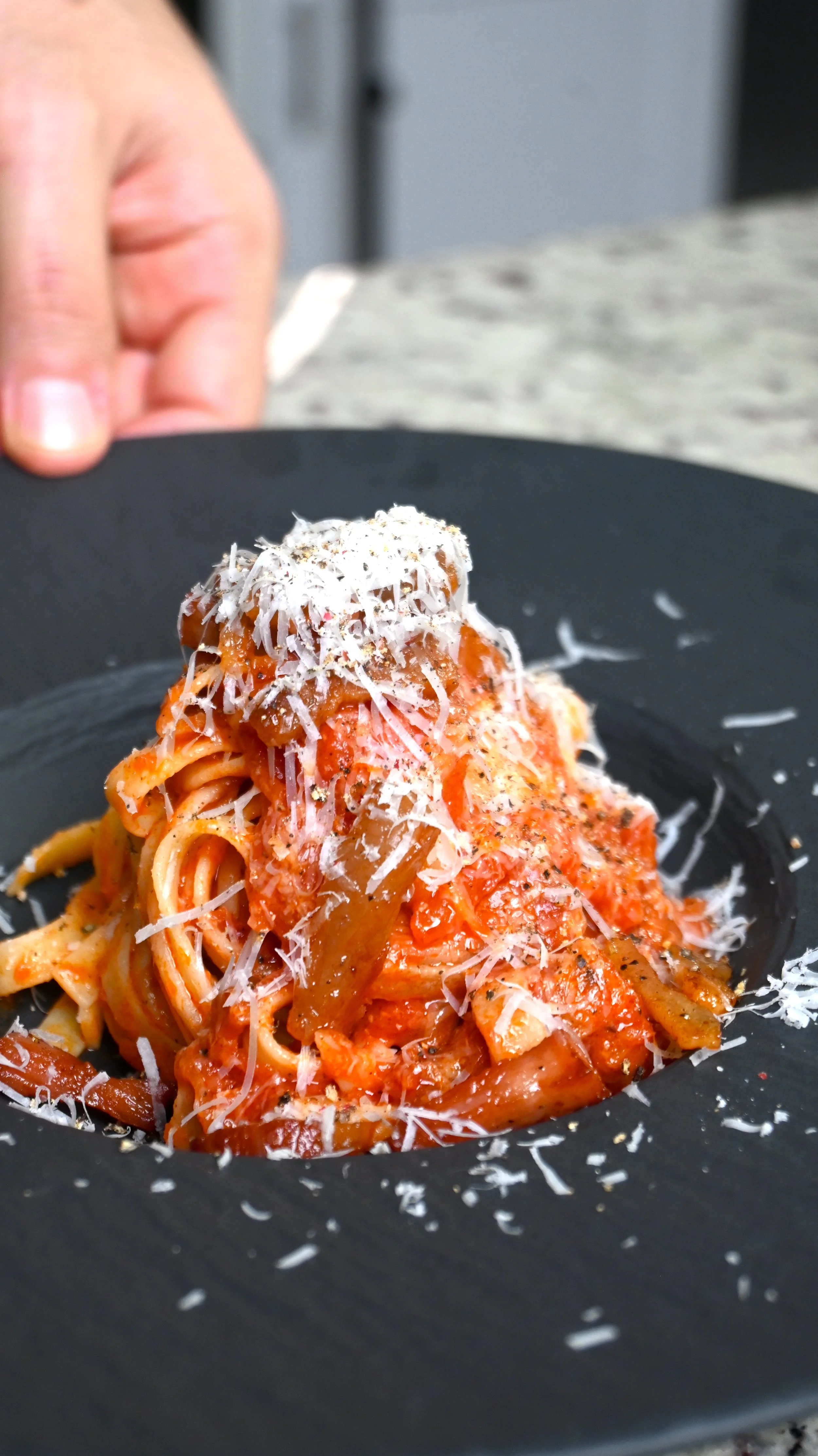 A plate of spaghetti with tomato sauce and grated cheese on top.