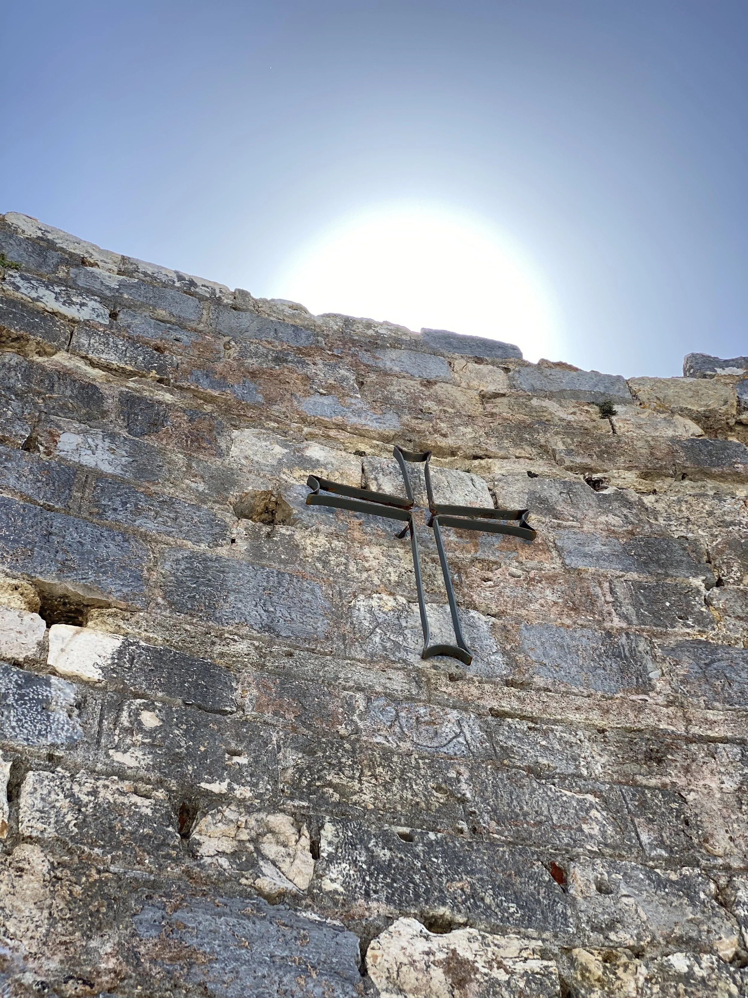 modern metal cross on the ancient apse wall commemorating the visit of a modern day pope