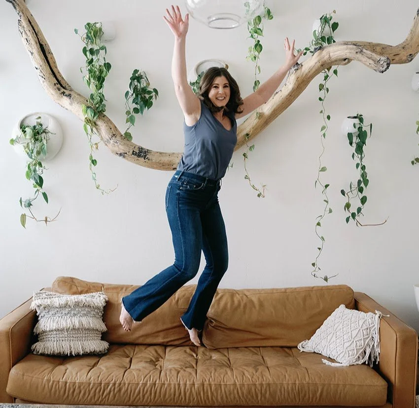 Katherine Libonate jumping for joy on a sofa