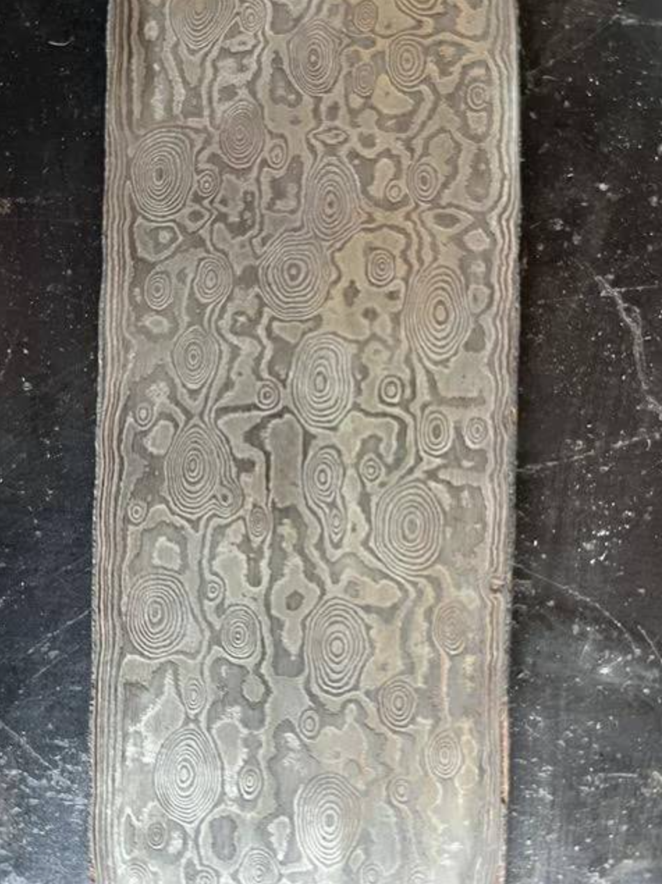  An example of a “raindrop” pattern damascus, made by layering nickel and steel, drilling divots and hammering the billet flat. 