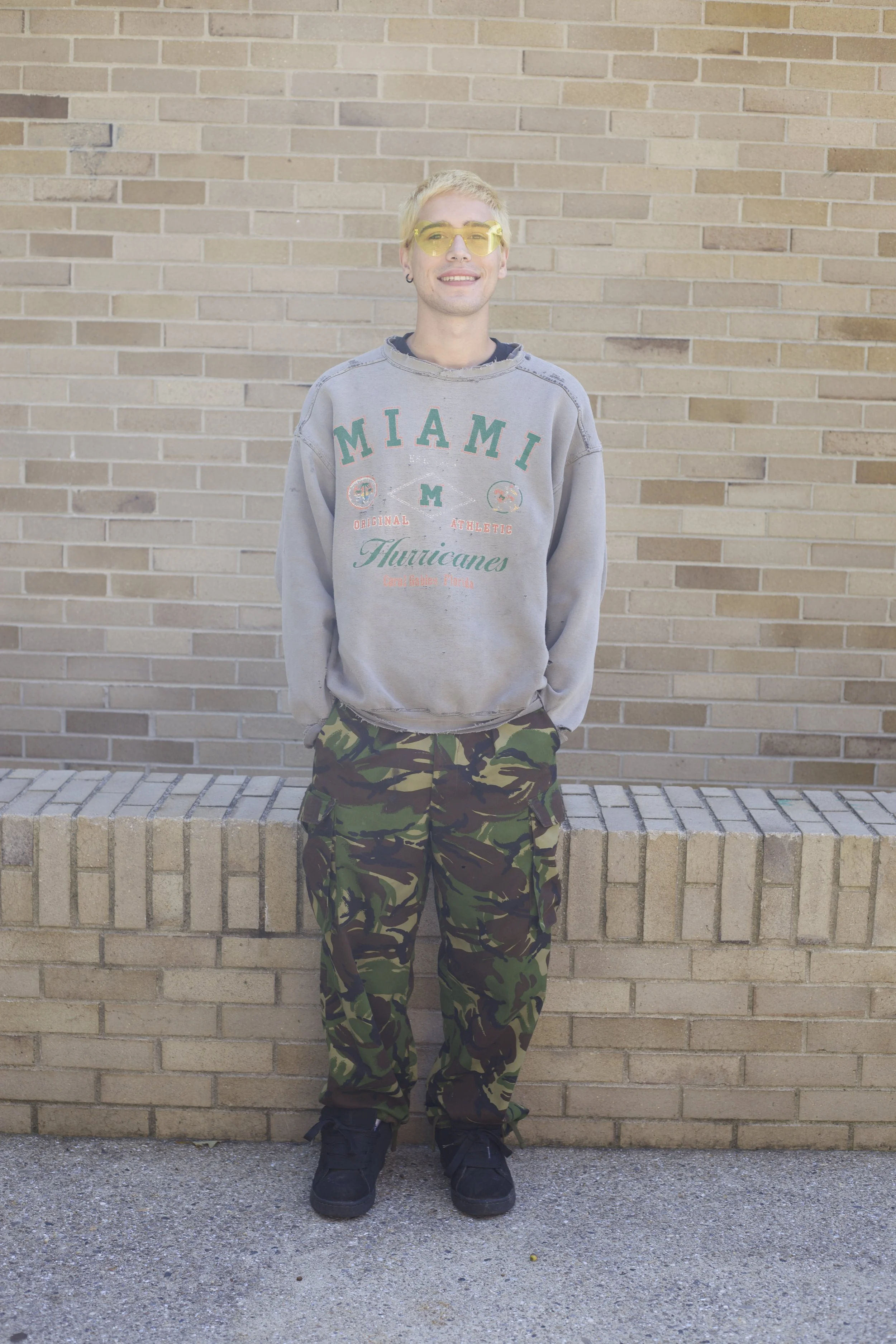 Julian Totten wearing thrifted army pants and a vintage 60’s sweatshirt paired with DC Court Graffik Skate shoes.