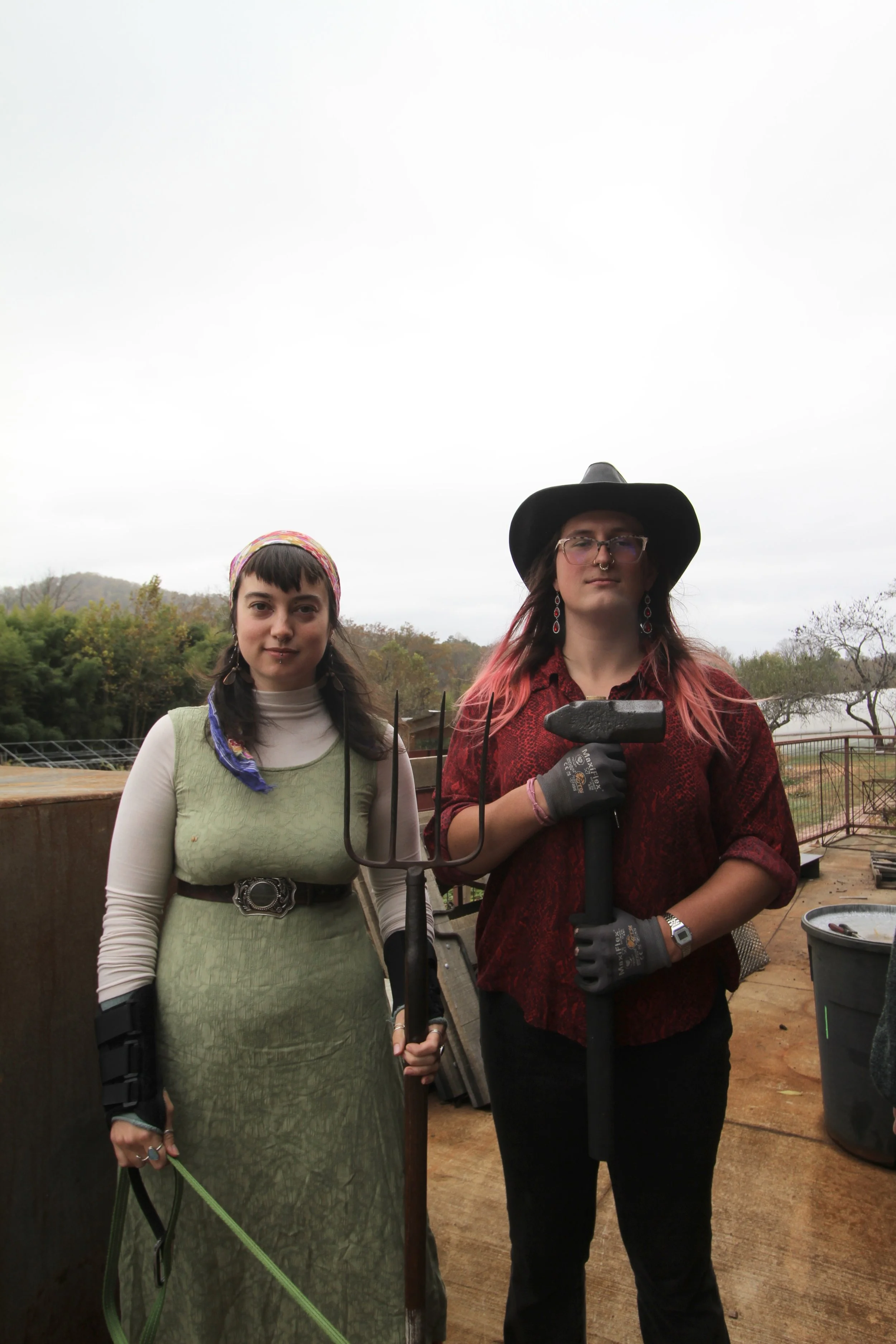  Junior blacksmithing crew members  Ivy Atkins  and  Marta Geilfuss  pose for a photo outside the forge on Nov. 4, 2025, in Swannanoa, N.C. (Echo/Vivian Bryan) 