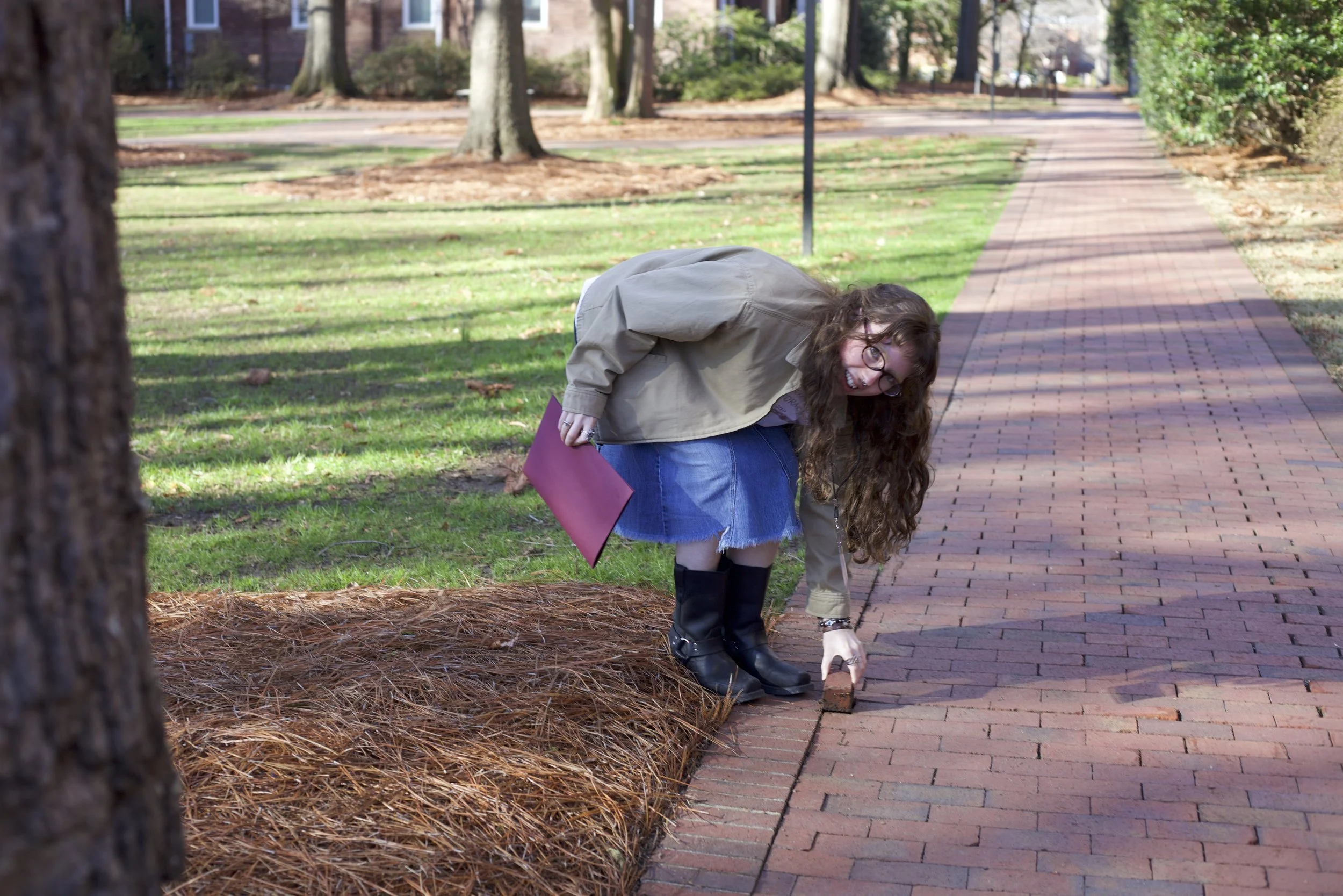  Echo editor Clara Shirley plucks a brick from the sidewalk at the NCCMA conference at Elon University, on Feb. 28, 2026 in Elon, N.C. (Echo/Emma Taylor McCallum) 