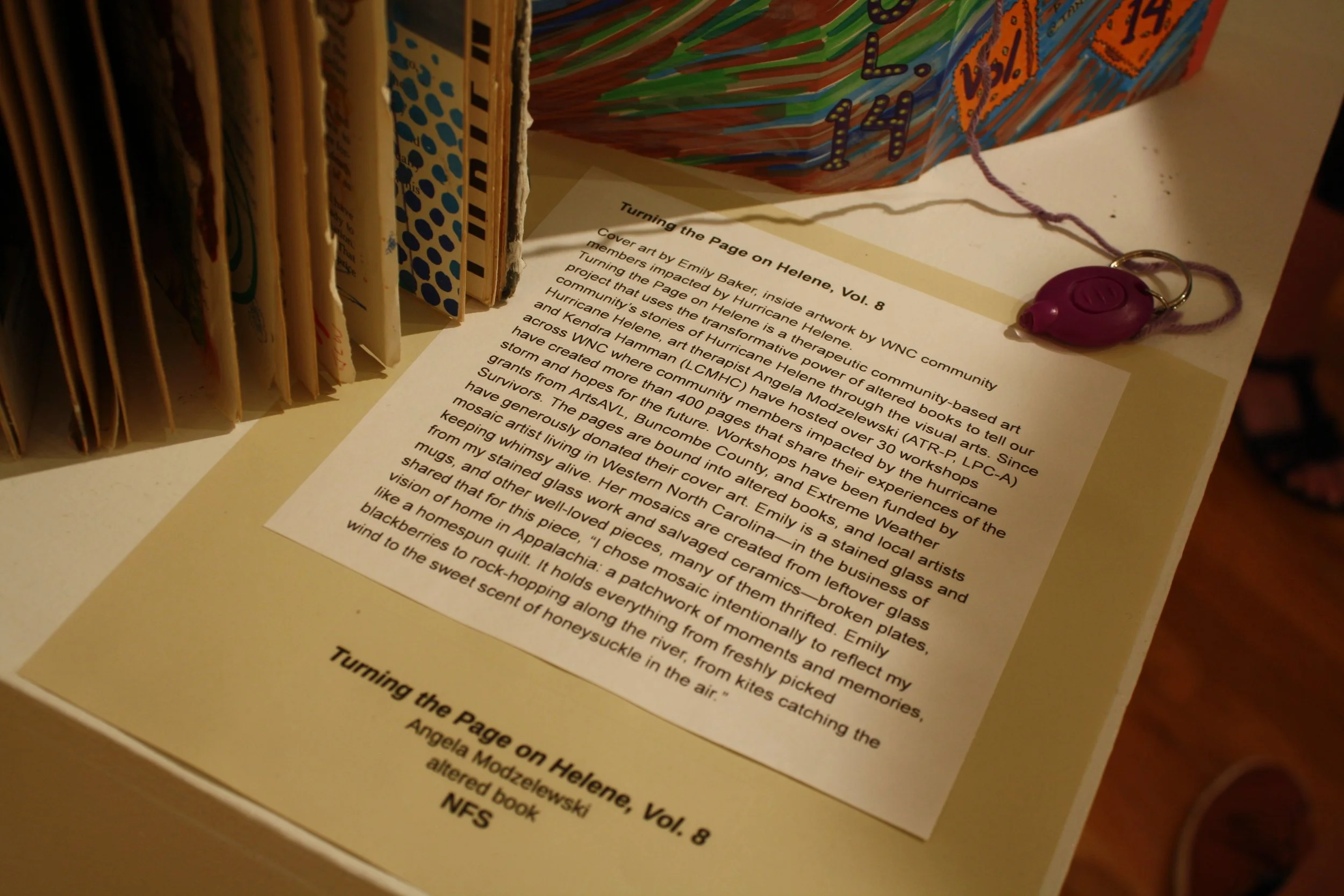  The artwork description card for Angela Modzelewski's community art project titled “Turning the Page on Helene vol. 14” displayed at the Contemplating Helene opening reception at the Black Mountain Center for the Arts, on Sep. 4, 2026, Black Mountai