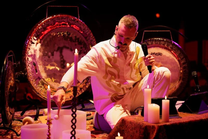 Man performing sound healing session with gongs and candles
