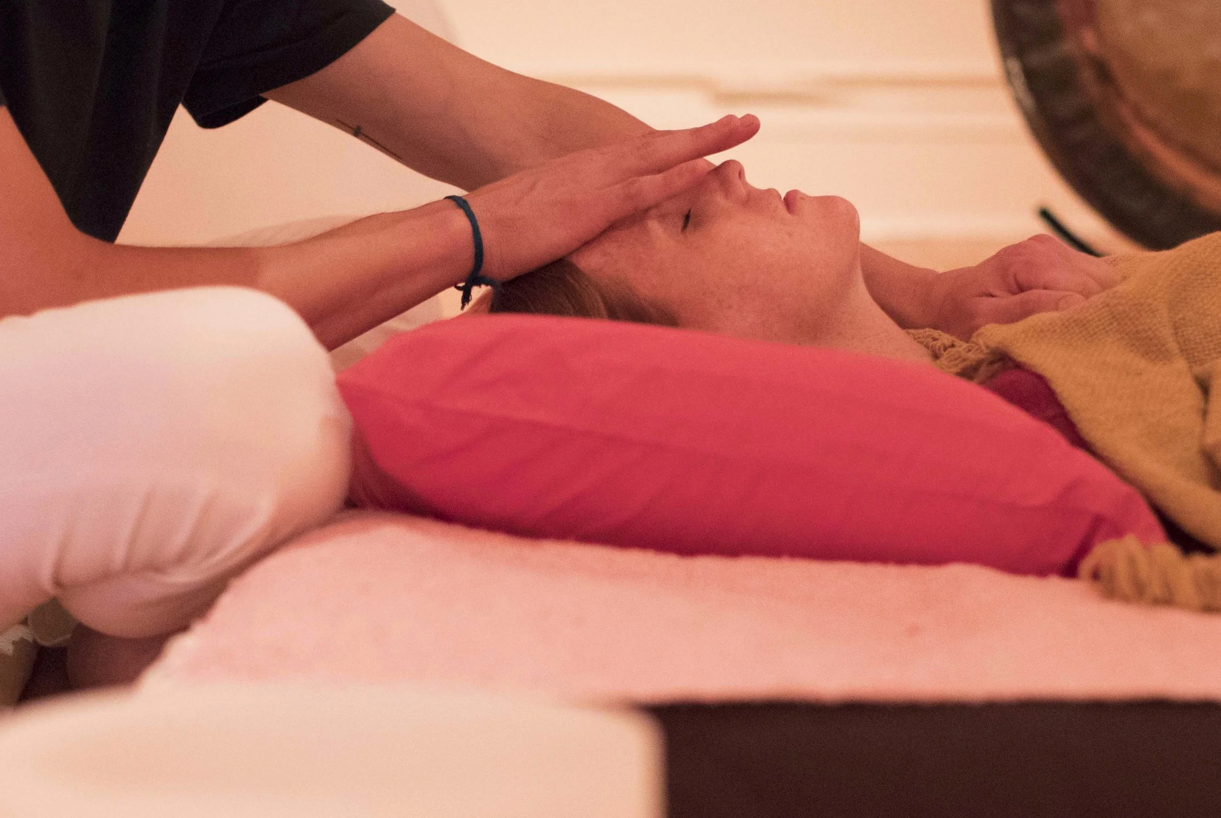 A person receiving a head massage on a pink pillow