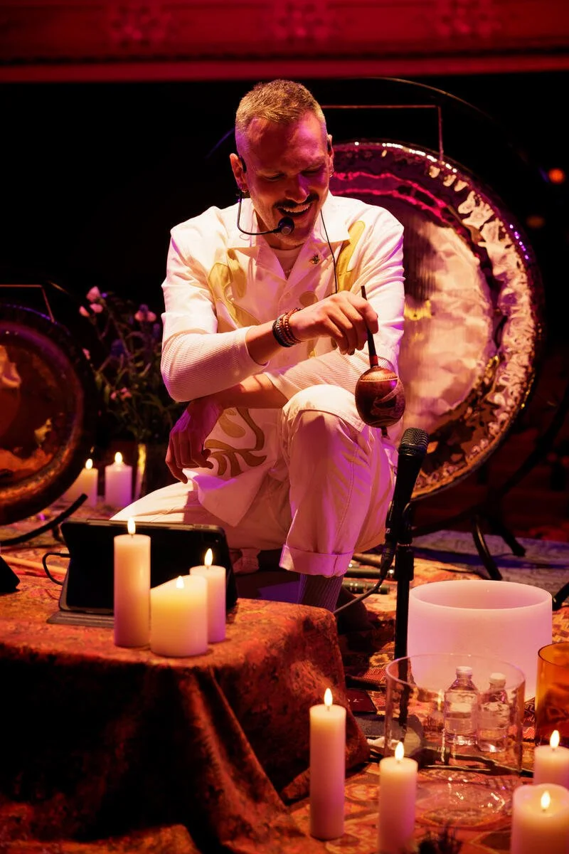 Man performing sound therapy with gongs and lit candles