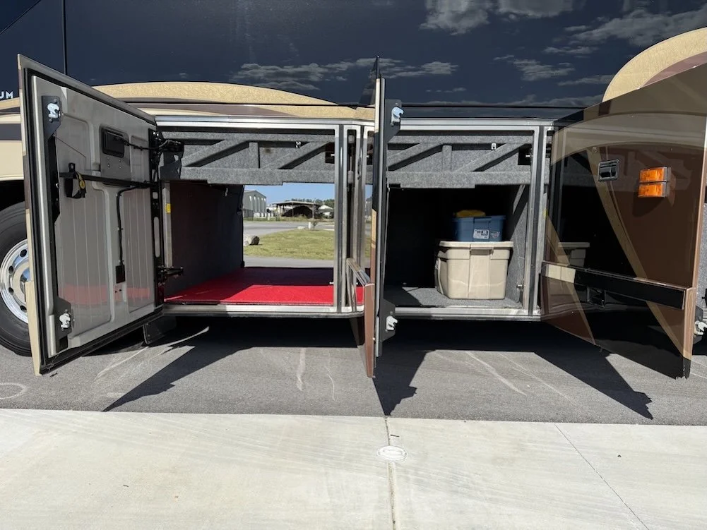 Wide view of open, carpeted basement storage bays under the motorhome.