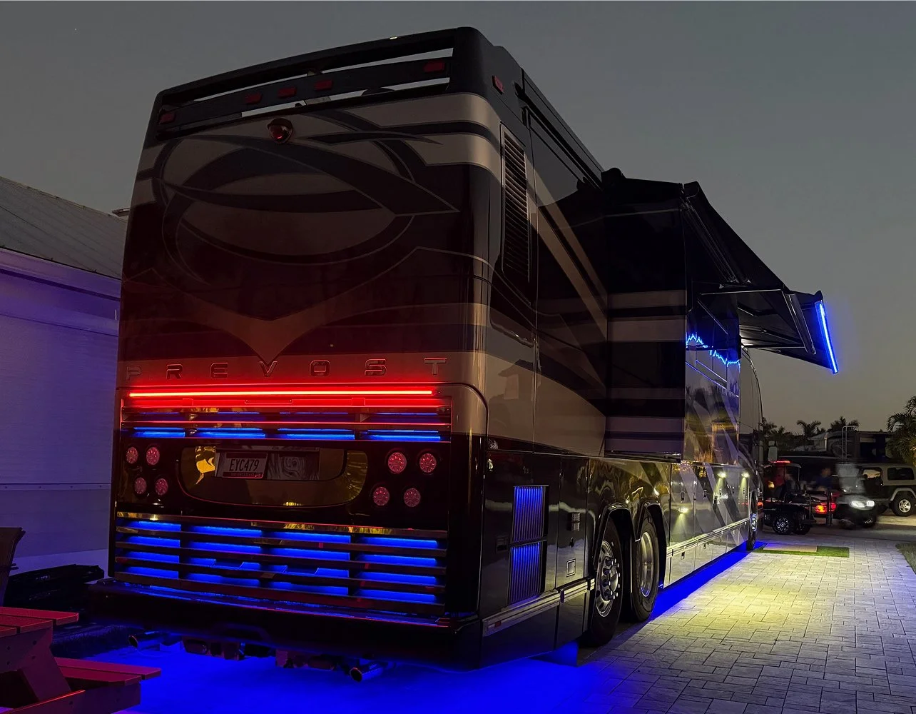ull rear view of a luxury coach at night showcasing integrated roofline, engine slat, and undercarriage accent lighting.