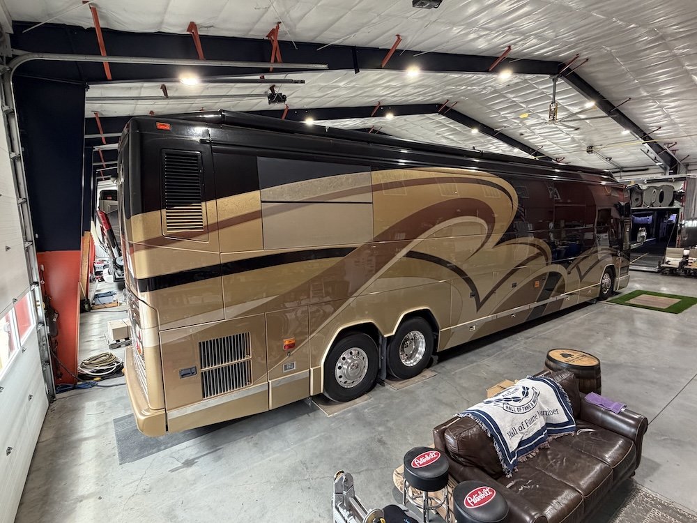 Rear passenger-side view of a Prevost Millennium coach in a garage.