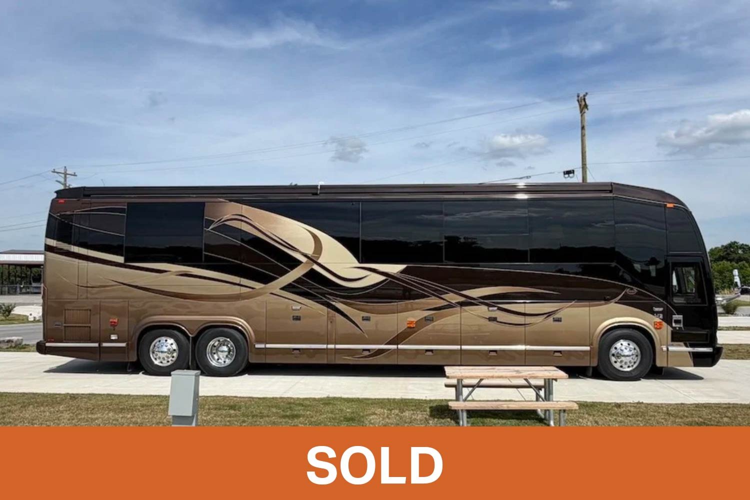 Side profile of a brown and gold custom 2008 Marathon luxury coach parked on a concrete pad.