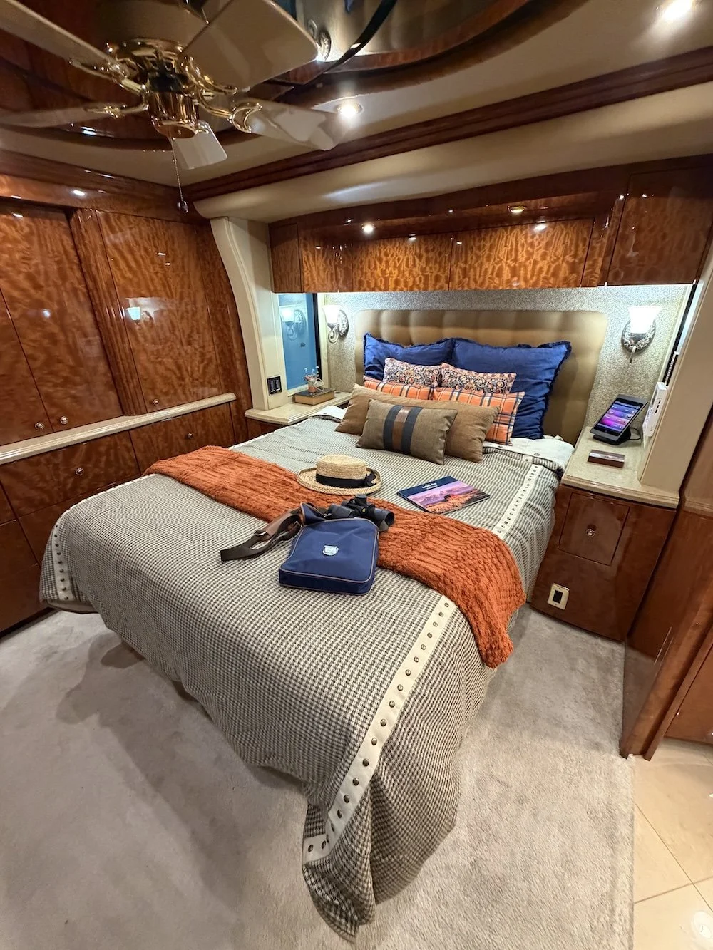 Luxury coach master bedroom with a made bed and polished wood cabinets.