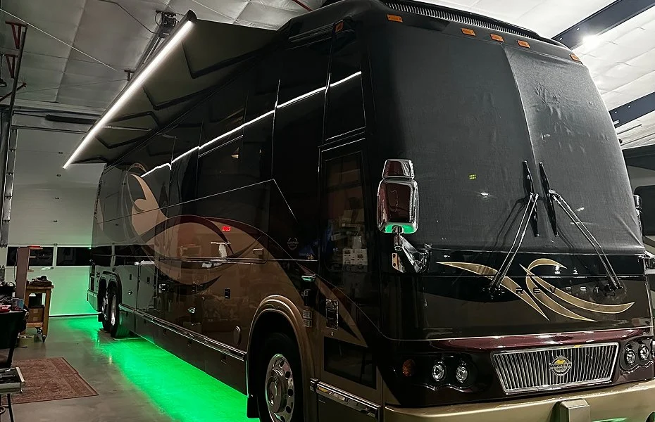 Luxury motorcoach parked at night featuring a vibrant, high-output green LED undercarriage light.