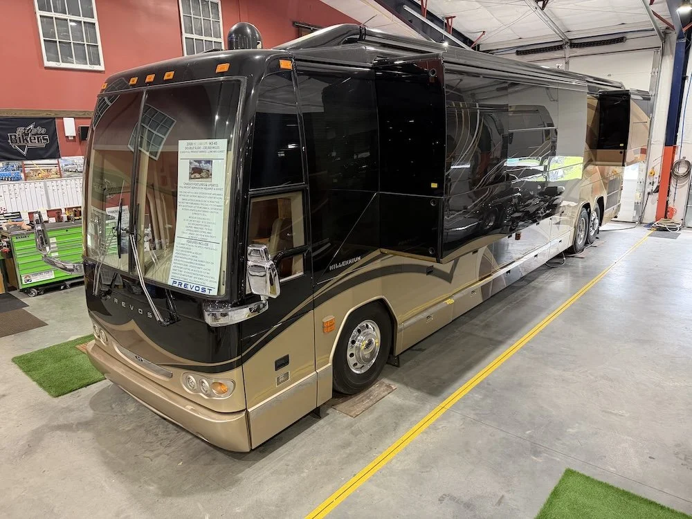 Front driver-side view of a 2008 Prevost Millennium coach indoors.