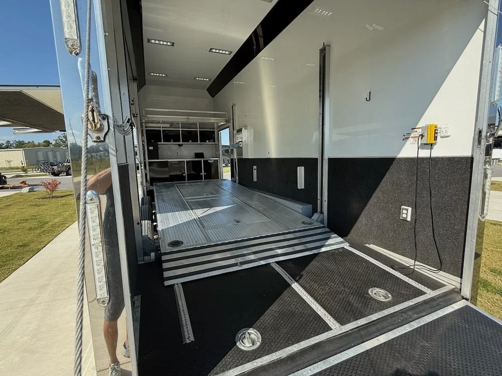 Interior of a trailer with a fold-out ramp, work station, and electrical outlets.