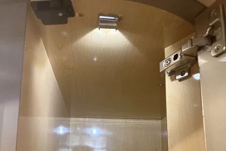 A compact Lumitec Andros LED courtesy light mounted inside a wooden cabinet.