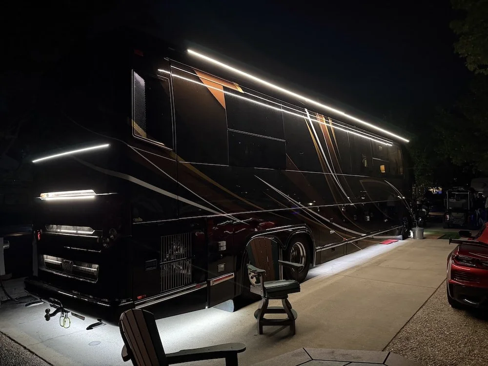 Side profile of a Marathon coach at night highlighting the illuminated rub rail and ground-effect undercarriage lighting.