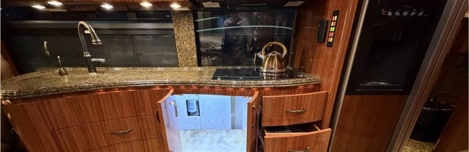 Wide view of a coach galley featuring warm under-counter accent lighting.