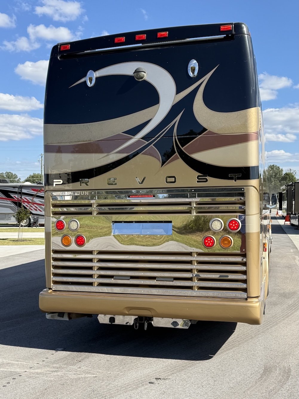 Close-up rear view of a gold and black Prevost coach.