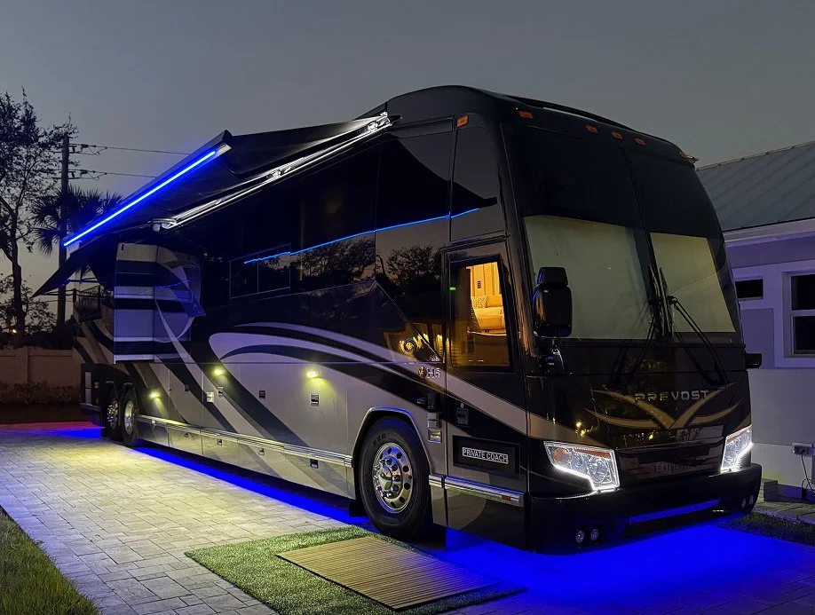 Luxury motorcoach at night with vibrant blue undercarriage and awning LED GLO.