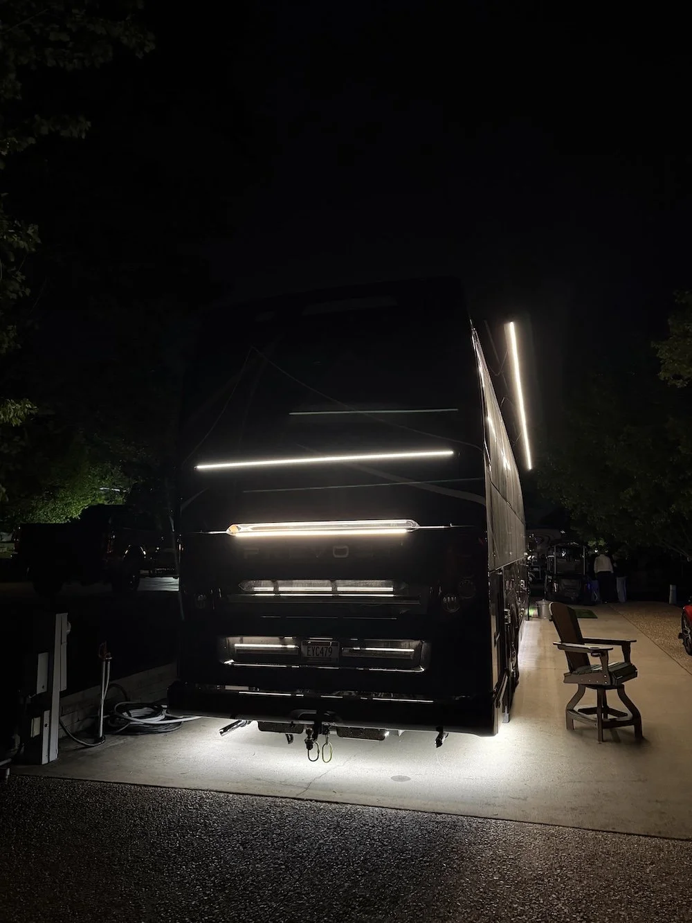 Rear view of a Prevost H3-45 at night featuring custom LED engine door and undercarriage glow kits.