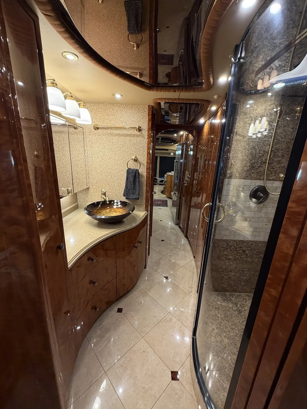 Bathroom vanity with a glass vessel sink and view of the glass shower.