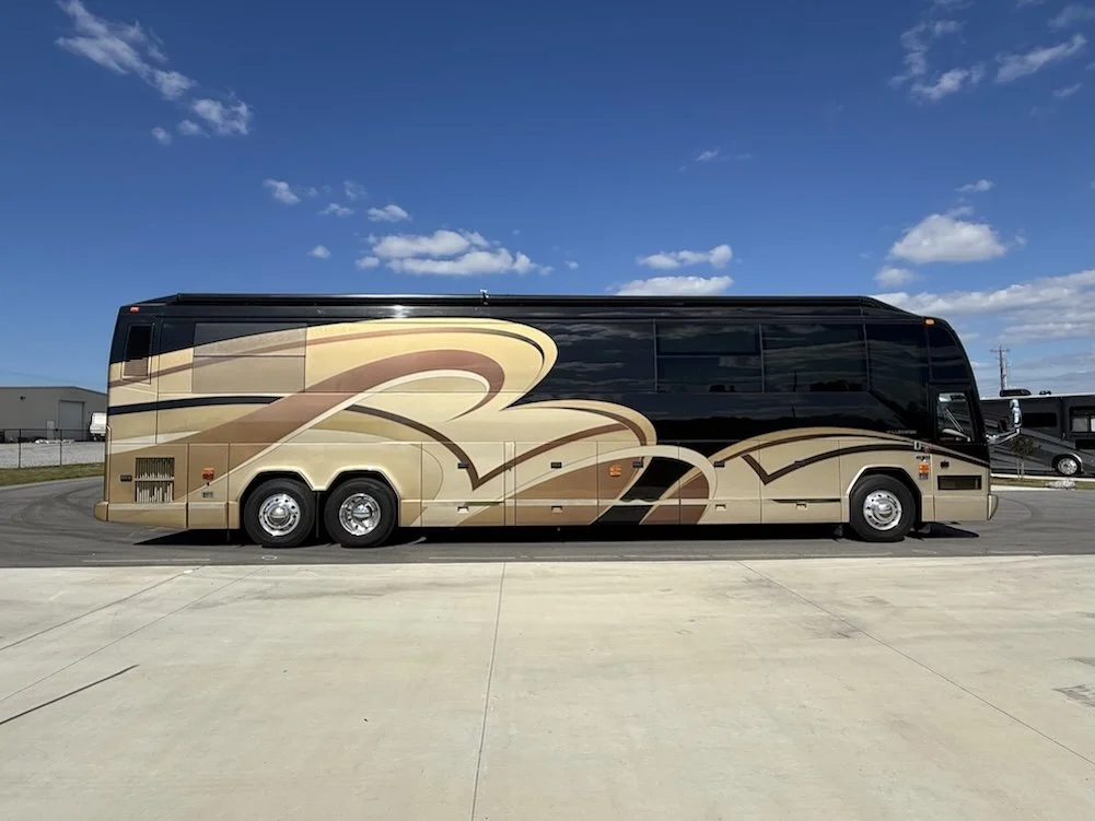 Side profile view of a black and gold Prevost Millennium coach.