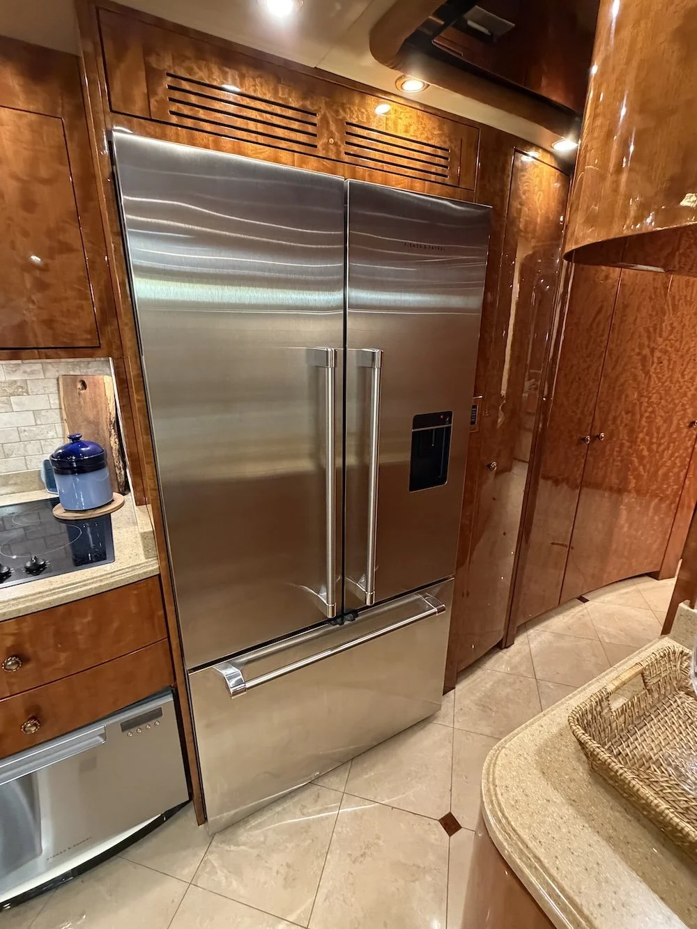 Stainless steel French door refrigerator integrated into wood cabinets.