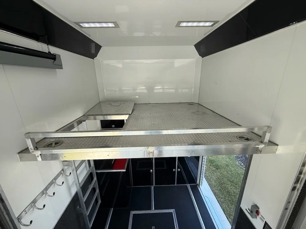 Interior of a trailer raised stainless steel shelf, a small countertop and hooks on the wall.