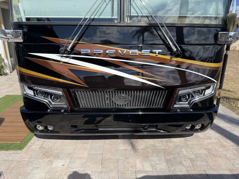 Close-up of the Prevost front grill, custom headlights, and polished chrome accents.