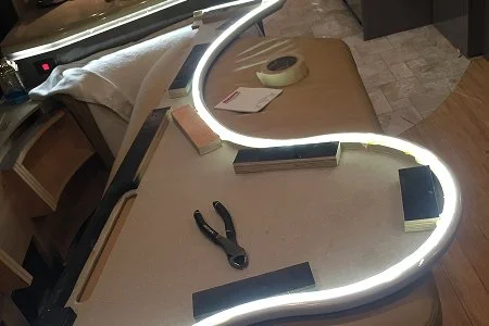 Close-up of a smooth, continuous LED GLO ribbon installed under a curved cabinet edge.